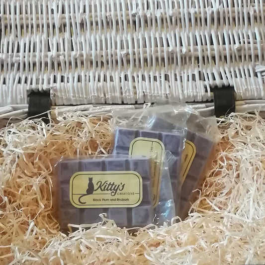 Three hand-made rectangular Wax Melts. Each is coloured a deep plum purple, the melts are resting in a basket of straw. Each melt is a beautiful fruity mixture of succulent black plum and rhubarb, interwoven with tender pear and English pear.