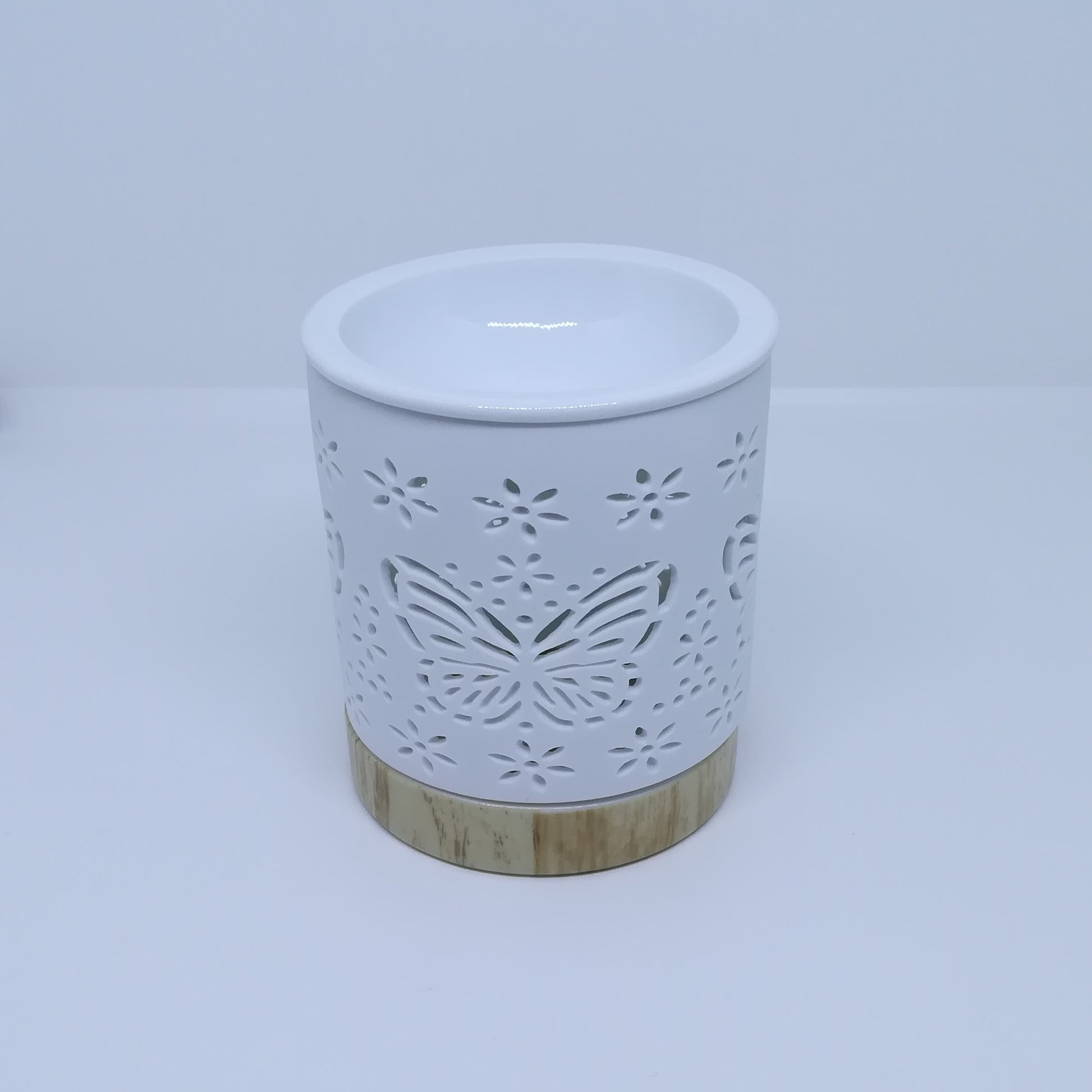 Ceramic white wax melt burner with ceramic wood effect base pictured under natural light.