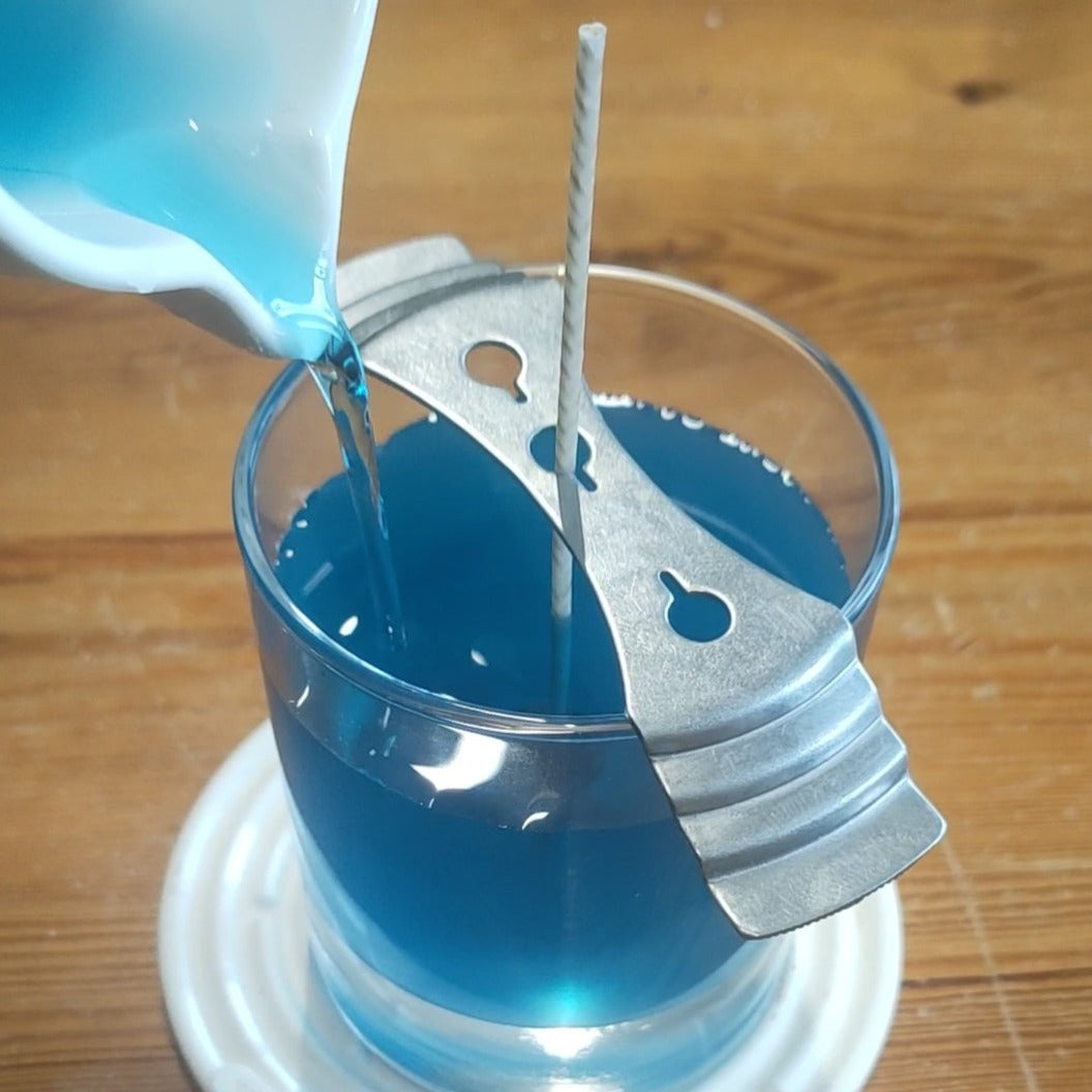 Candle workshop available for adults from Kitty's Creations near Oswestry.  The picture shows blue liquid wax being poured from a white jug into a glass candle, as it's being made.