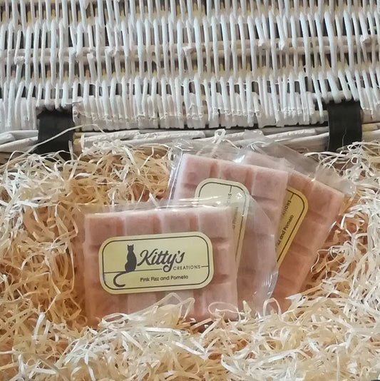 Three hand-made rectangular Wax Melts. Each is coloured a delicate pink and resting in a basket of straw. This is fragrance lets you smell the celebrations as the bubbles fizz and the celebrations begin