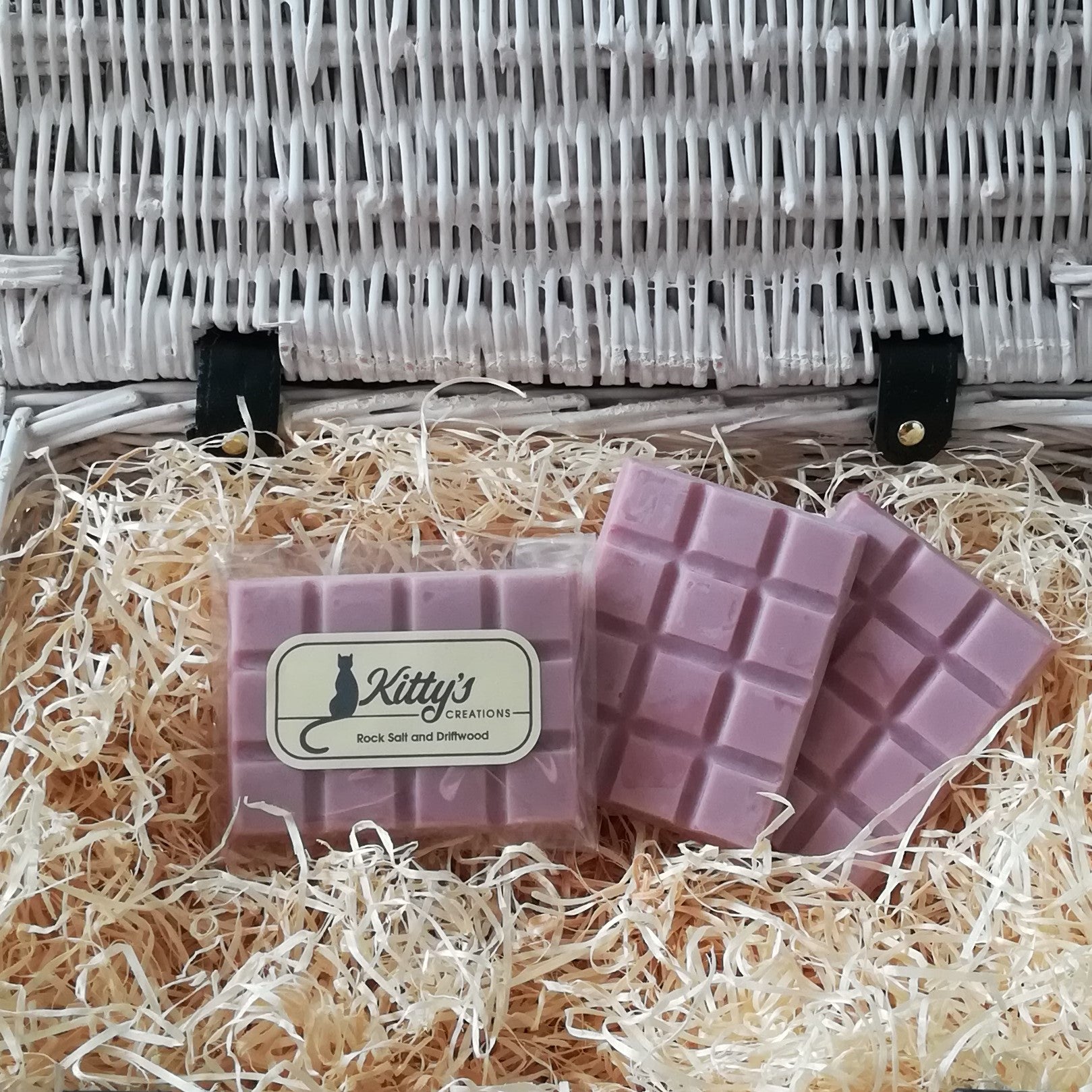 Three hand-made rectangular Wax Melts. Each one light mauve - pink resting in a basket of straw, The light fresh aroma reminiscent of days spent rock-pooling, a marine scent with coastal breezes mixed with seaweed, waterlily, and salt crusted driftwood with the masculine warmth of amber patchouli and musk.