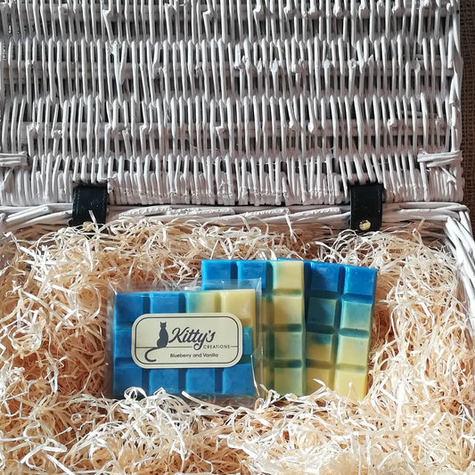 Three hand-made rectangular Wax Melts. Each is blended from dark blue to pale yellow, coloured to show the succulent balance of aromas within. Each melt is resting in a basket of straw and scented to stimulate your taste buds.