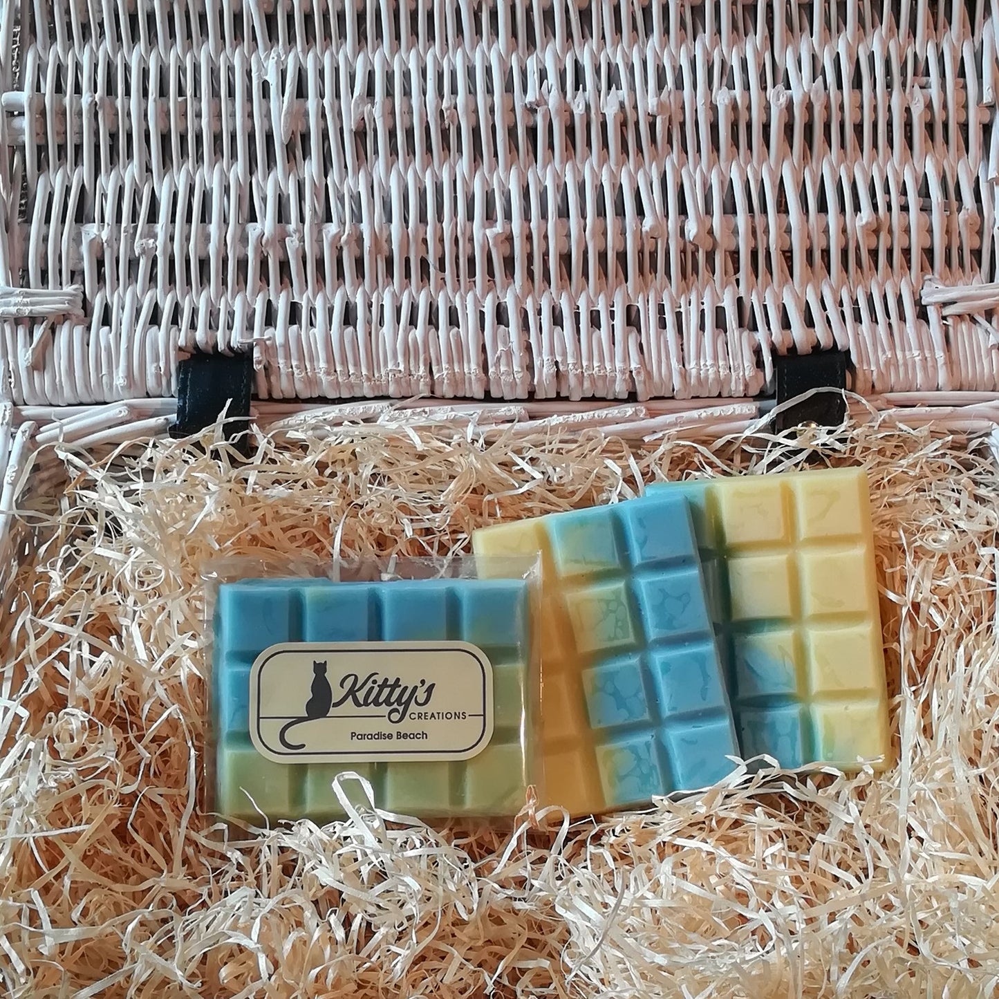 Three hand-made rectangular Wax Melts, each one coloured like a perfect tropical sea lapping over golden yellow sands, resting in a basket of straw. Each melt reveals a scent evoking the memory of warm sunshine caressing your skin as waves gently lap around your ankles.