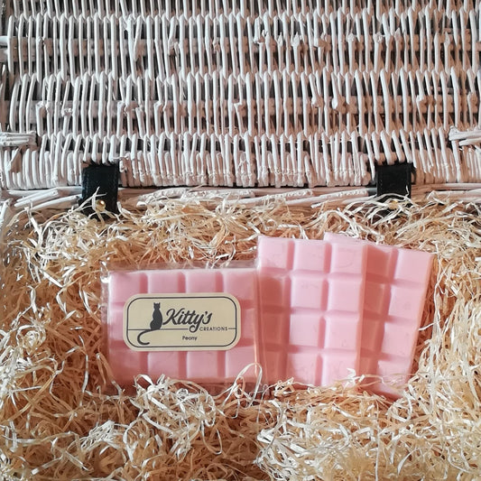 Three hand-made rectangular Wax Melts. Each is a delicate pastel pink resting in a basket of straw. Each melt effortlessly releases the light subtle aroma of Peony allowing the cool freshness of a late Spring morning to drift around your home.