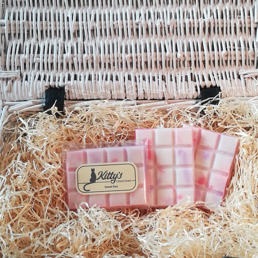 Three hand-made rectangular Wax Melts. Each is white Soy wax, coloured with gentle Sweet Pea marbling patterned in their delicate pink and purple shades, the melts are resting in a basket of straw. Each melt is alive with Sweet Peas, giving you the uplifting fragrance of walking through flowering archways and pergolas.