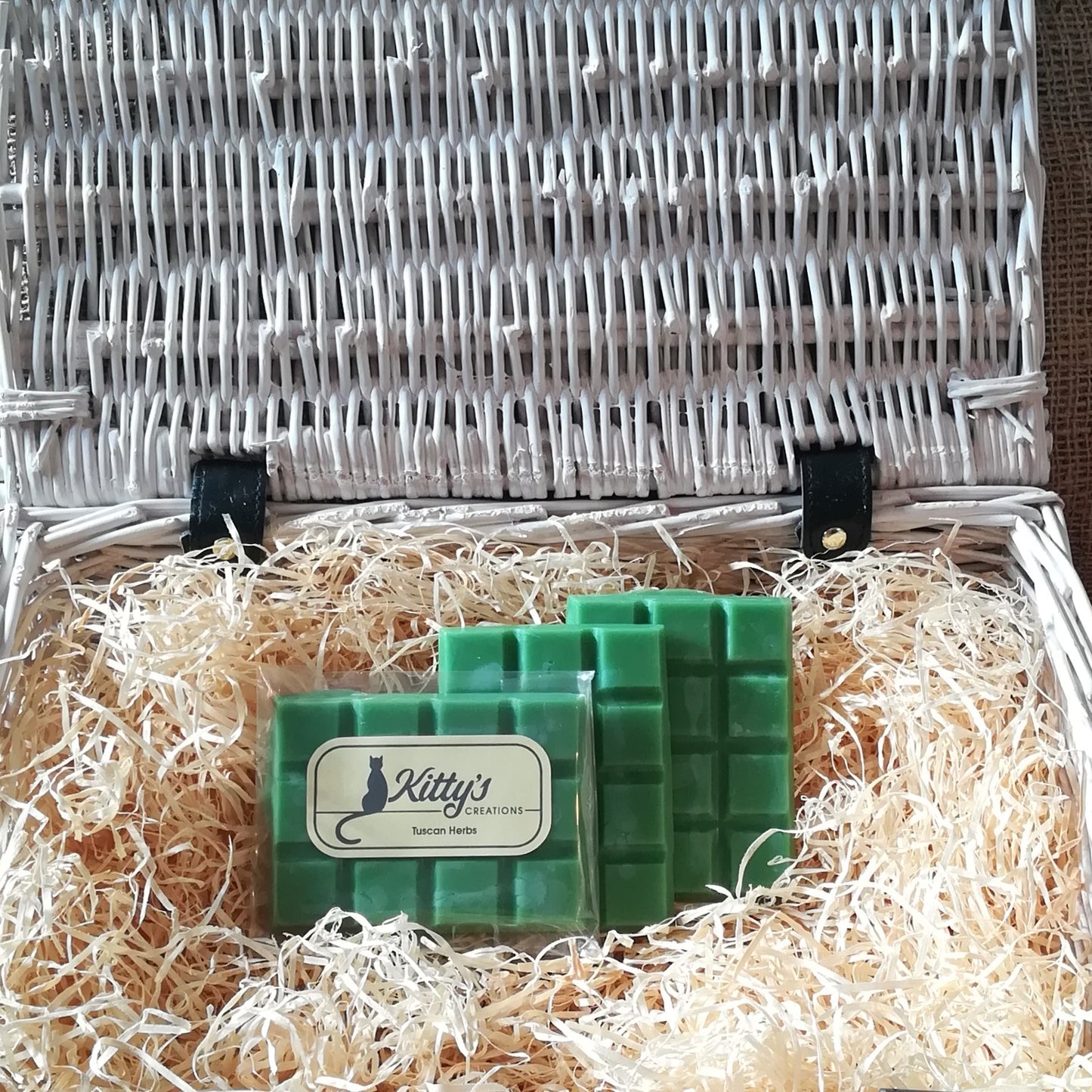 Three hand-made rectangular Wax Melts. Each is coloured like a deep green like a Mediterranean field, the melts are resting in a basket of straw. Each melt is a classic rural blend that begins with hand rubbed tomato leaves, fresh lemon groves and orange trees heavy with sun ripened fruit, before leading you down cobbled streets with crushed oregano and aromatic woods as you relax in the Mediterranean countryside.