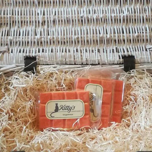 Three hand-made rectangular Wax Melts. Each is coloured a vibrant orange, and resting in a basket of straw. Imagine the smell of fresh gingerbread emerging from the oven, waiting for it to cool while you warm yourself in the kitchen.